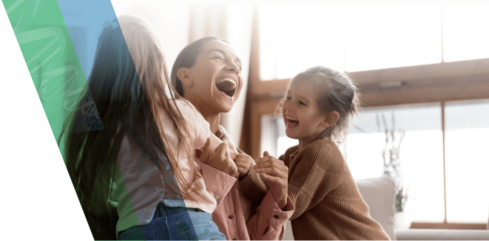 A laughing mother is embraced by two happy children.